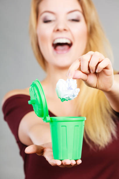 istock Woman putting paper into small trash can 649684174
