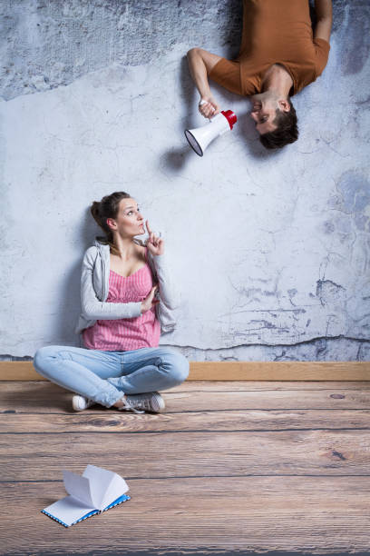istock Woman quieting man with megaphone 649687618