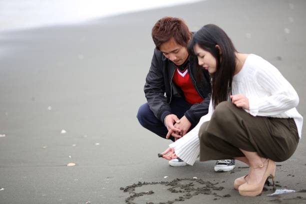 istock HIgh School Student Couple Writing Heart Shape in Sand 649693040