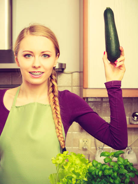 istock Woman in kitchen holds zucchini vegetable 649698552