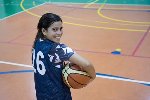 Girl standing with ball in basketball court