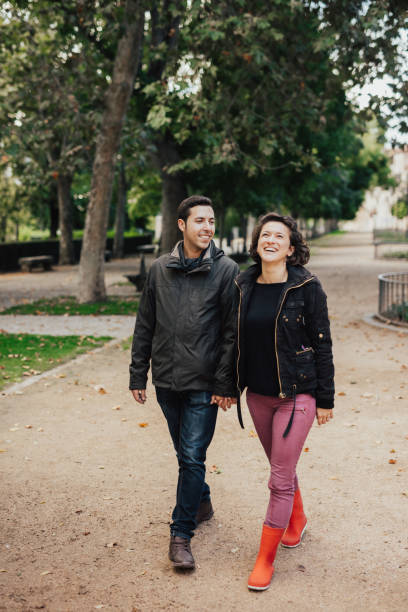 istock Smiling couple holding hands and strolling through the park 649704270