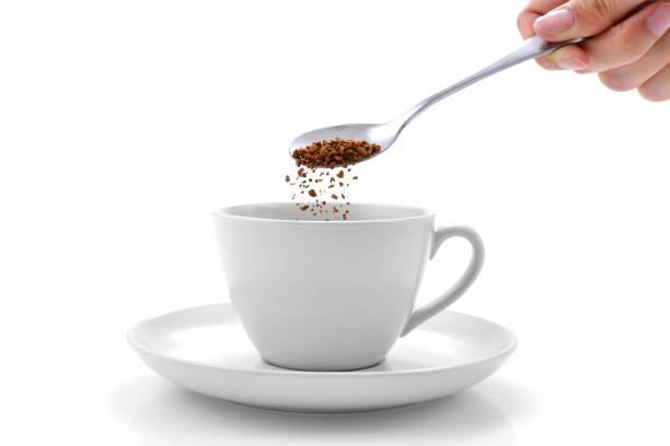 Coffee Hand pours instant coffee from a spoon in a coffee cup instant coffee stock pictures, royalty-free photos & images