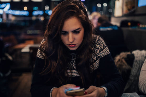 istock Girl with serious facial expression using smart phone in the pub 649714944