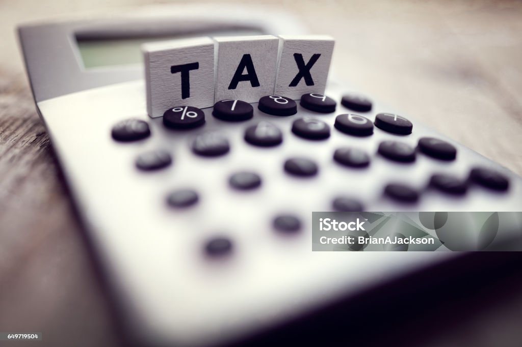 Calculating Tax Calculator with the word tax written in wooden block letters Tax Form Stock Photo