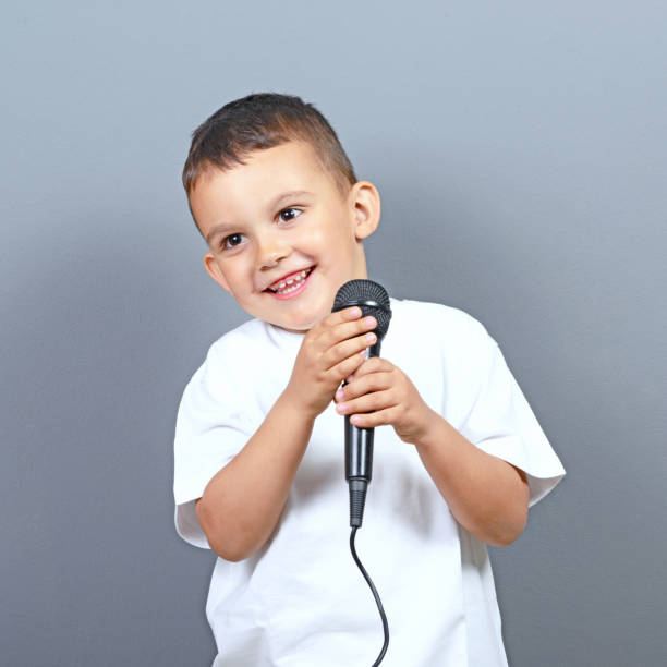 istock Cute little boy kid singing on microphone against gray background 649722054