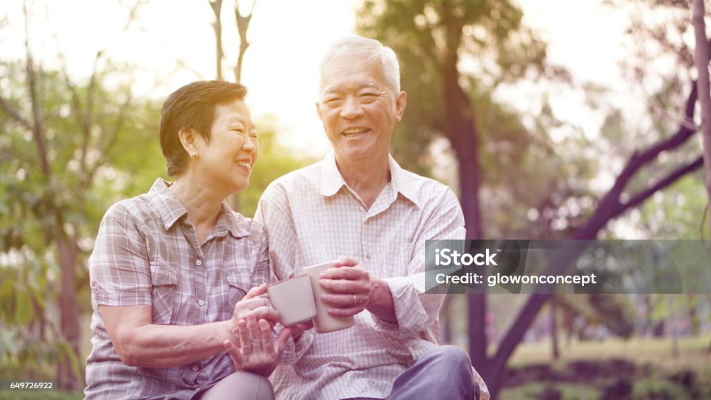 Healthy Asian senior couple drinking coffee in morning park together Planning Stock Photo