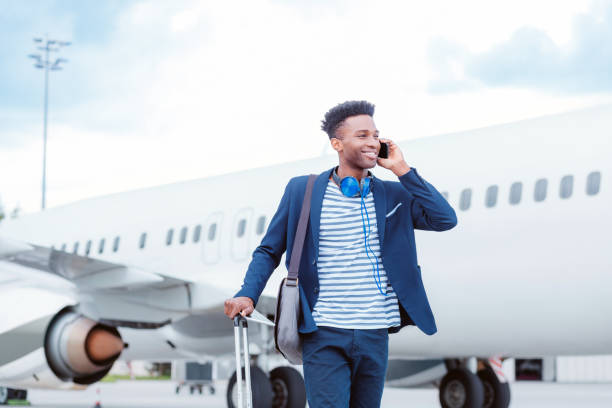 jovem empresário falando no telefone inteligente na frente do avião - men smiling headphones individuality - fotografias e filmes do acervo