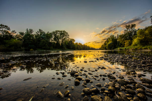 Scenic view of Mura river amidst forest. Tranquil view of water and pebbles against sky during sunset. Beautiful view of nature.