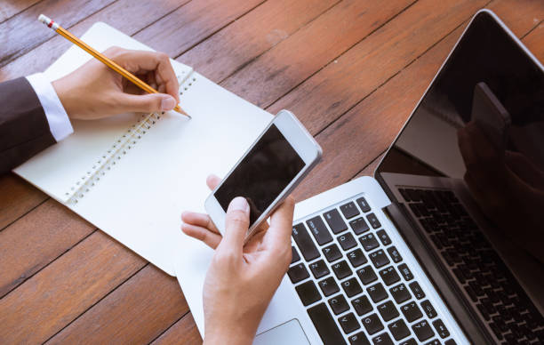 istock Business woman write on notebook and use cell phone working. 649734408