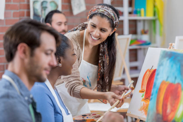 l'istruttore d'arte felice aiuta le studentesse - easel artists canvas paint paintings foto e immagini stock