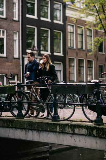 istock Young couple standing on the bridge, drinking coffee from takeaway cups. bicycle leaning on the fence 649738396