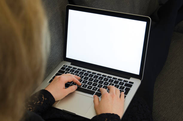 istock Blond woman typing on a laptop with blank white illuminated computer monitor 649738882