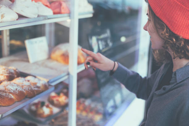 istock Curly woman standing in front of showcase with sweets 649741496