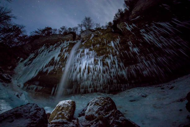 Low angle view of Pericnik Falls. Idyllic waterfall is surrounded by icicles in Triglav National Park. Rocky mountain at night at Slovenia.