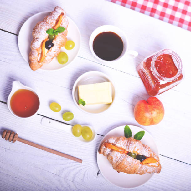 istock Fresh fruit croissant with coffe, butter, honey and peach on white background 649746124