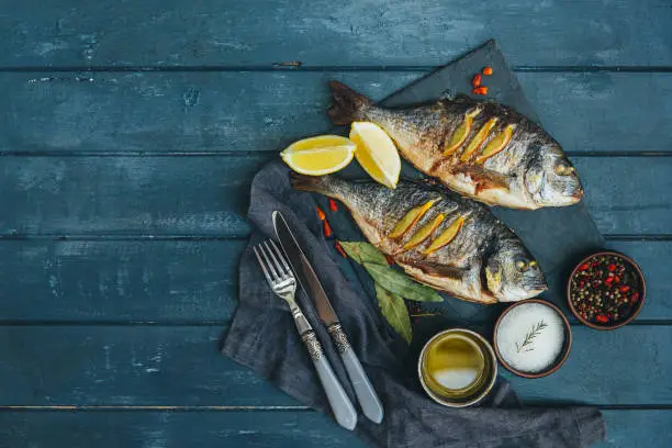 Photo of Fish Meat on a Black Tray with Herbs and Spices on Top of a Rustic Wooden Table