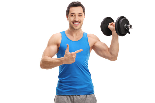 Happy young man lifting a dumbbell and pointing isolated on white background