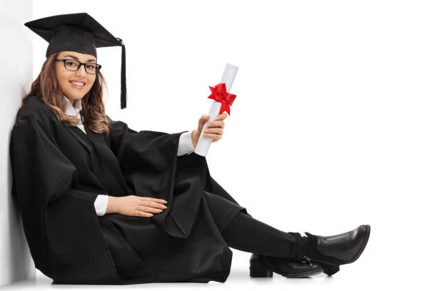 istock Happy graduate student with a diploma sitting on the floor 649749590