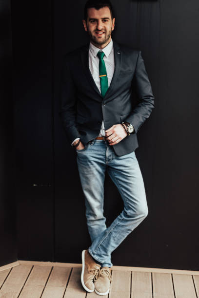 istock Smiling man in a suit leaned on a black wall 649761222