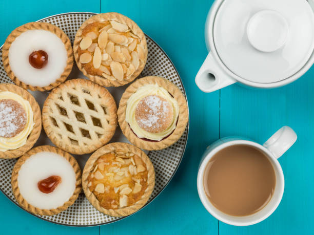 plate of assorted individual cakes or tarts with a pot of tea - tea berry currant fruit imagens e fotografias de stock