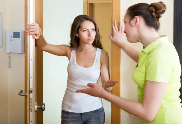 Displeased young woman visiting neighbour  at the door