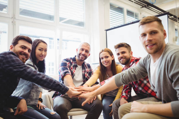 istock Portrait of smiling creative business people stacking hands 649772284