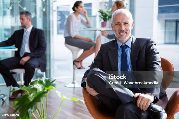Smiling Businessman Sitting On Chair In Office Stock Photo - Download Image Now - 40-44 Years, 20-24 Years, 30-34 Years