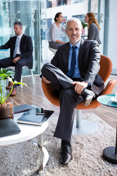istock Smiling businessman sitting on chair in office 649774086