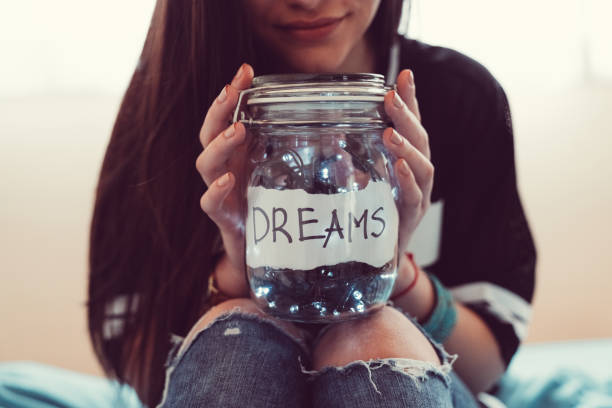 Teenage girl sitting in bed and holding jar