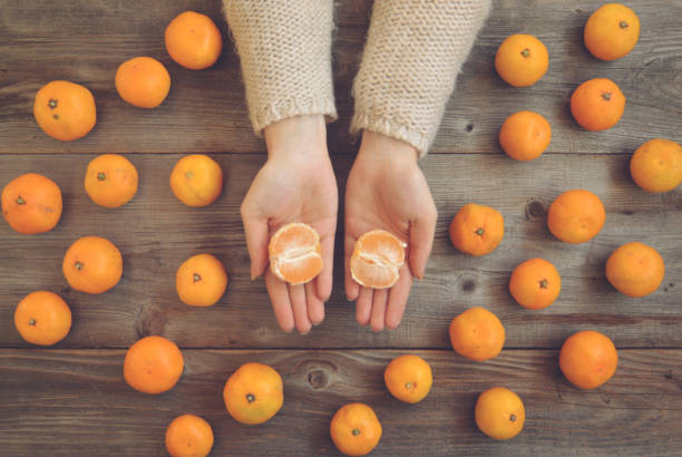 plano pone vista de manos de mujer pelar mandarinas frescas en la mesa de madera - concepto de otoño - mano sobre cadera fotografías e imágenes de stock