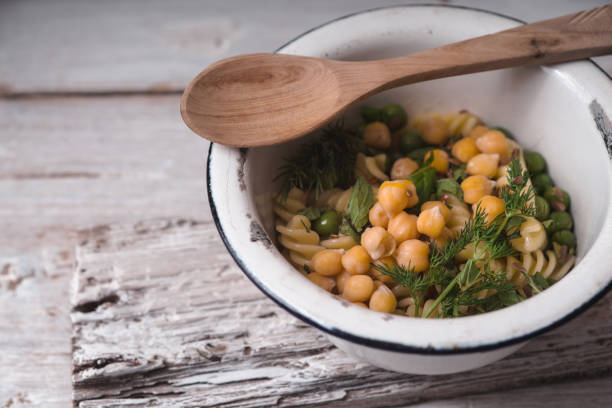 Salad with fusilli, chickpeas and peas in a white bowl horizontal