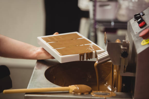 istock Worker filling mould with melted chocolate 649782352