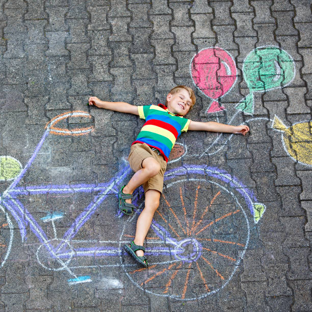 istock little kid boy having fun with bicycle chalks picture on ground 649787164