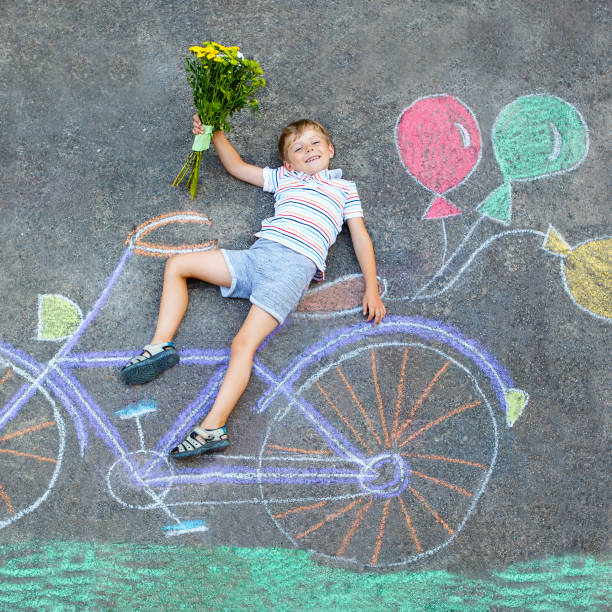 istock little kid boy having fun with bicycle chalks picture on ground 649787936