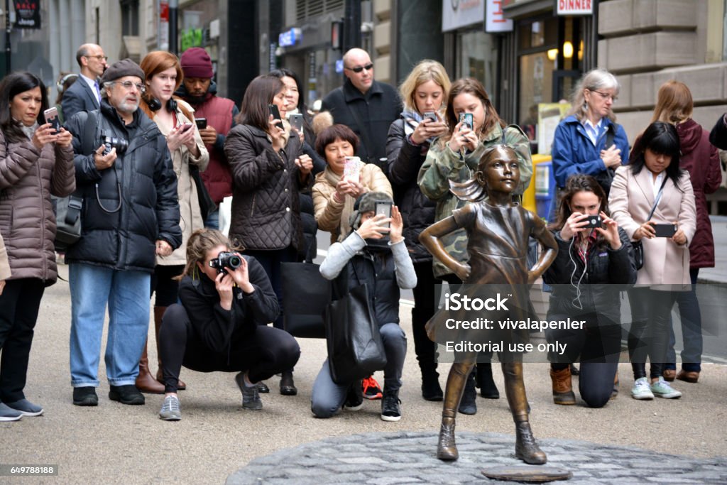 Fearless Girl People gathering around "The Fearless Girl" statue placed in Lower Manhattan to help mark International Women's Day. Fearless Girl Statue Stock Photo