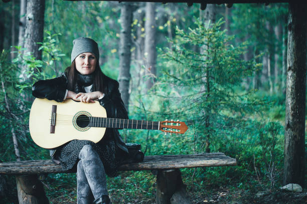 Women Playing the Guitar and Sings in the Forest