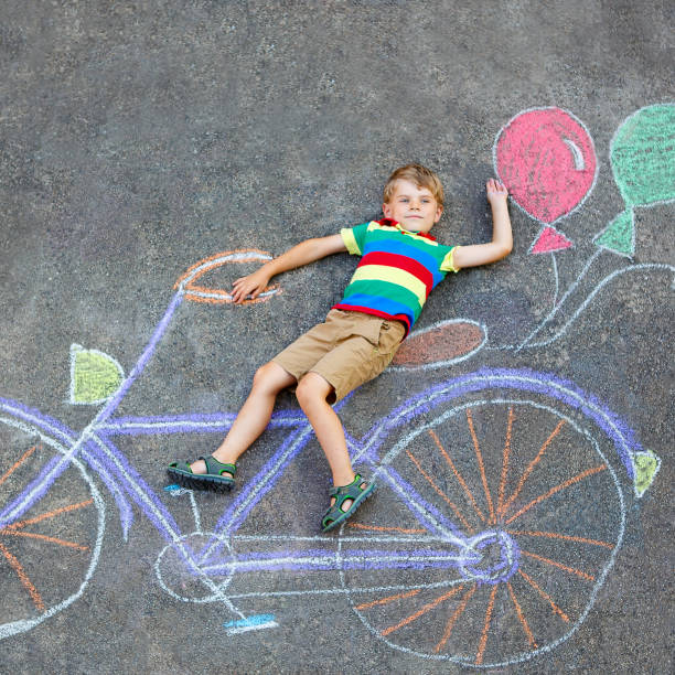 istock little kid boy having fun with bicycle chalks picture on ground 649791442
