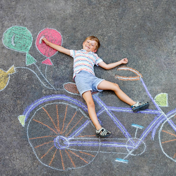 istock little kid boy having fun with bicycle chalks picture on ground 649791886