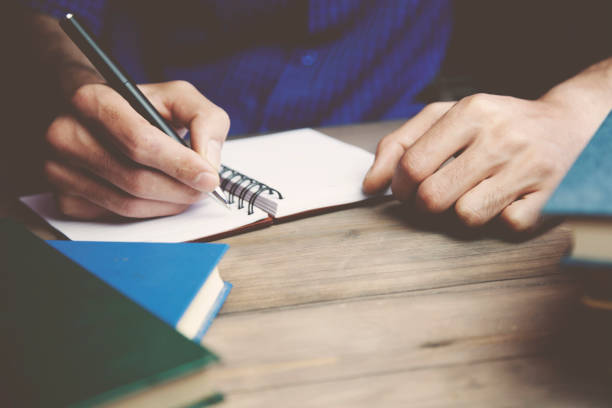istock man hand pen and books and notebook on tabl 649791988