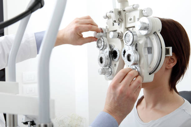 woman doing eyesight measurement with optical phoropter woman doing eyesight measurement with optical phoropter optometry photos stock pictures, royalty-free photos & images