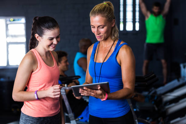 amici sorridenti con tablet digitale in palestra - fitness instructor foto e immagini stock