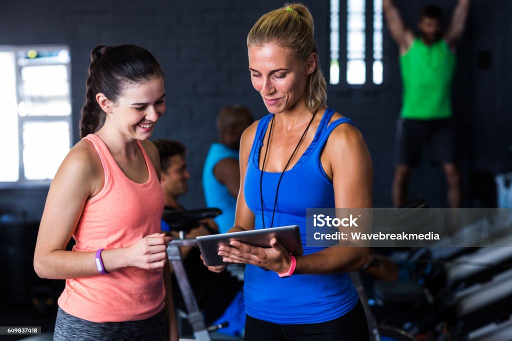 Smiling friends with digital tablet in gym Smiling friends with digital tablet while standing in gym Fitness Instructor Stock Photo