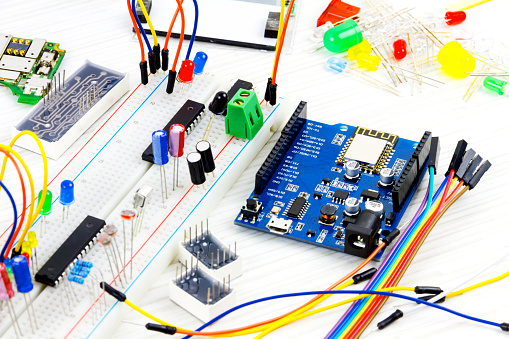 Microcontrollers, chips, resistors and light-emitting diodes on white desktop of hardware engineer. Engineer workplace