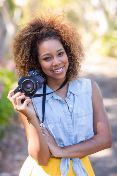 istock Smiling woman standing with digital camera 649855582