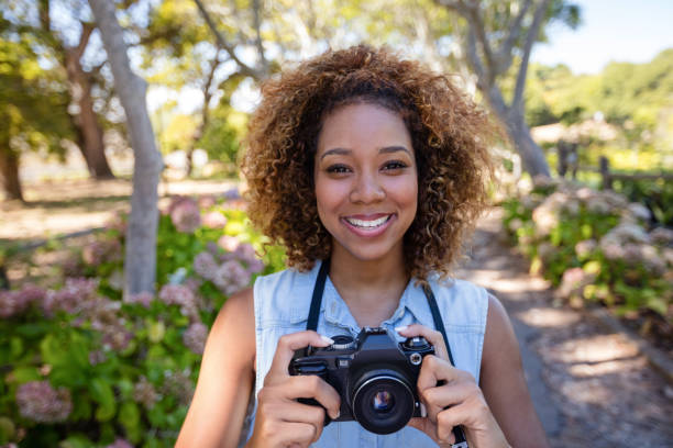istock Smiling woman standing with digital camera 649855696
