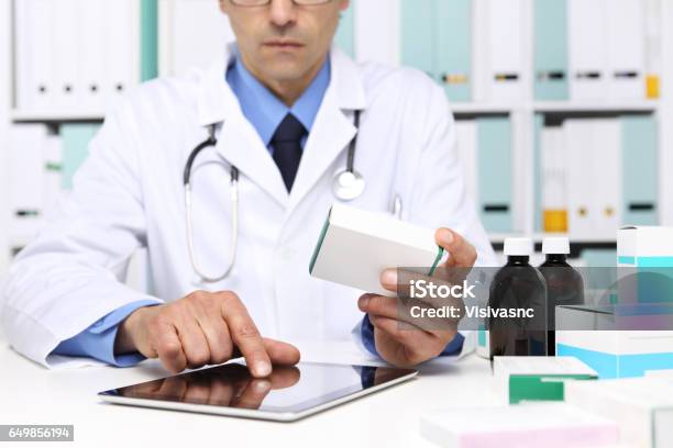Doctor Reading A Digital Tablet With Drug Boxes In Hand At Office Desktop Health Care Medical And Pharmacy Concept Stock Photo - Download Image Now