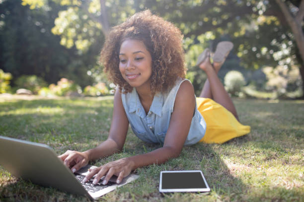 istock Smiling woman lying on grass and using laptop 649856630