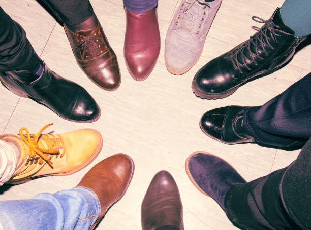 10 women colleagues at the office showing unity with their legs together standing in a circle