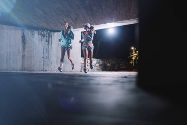 istock Two young women jogging at night in city 649867024